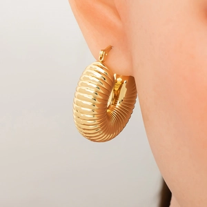 Close-up of gold croissant twist hoop earring with 18K plating and metallic texture