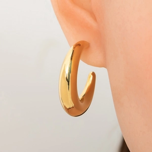 Close-up of chunky 18K gold plated teardrop earrings on a model showing polished finish