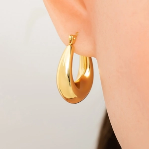 Detailed close-up of chunky gold teardrop hoop earrings on model for size and gloss