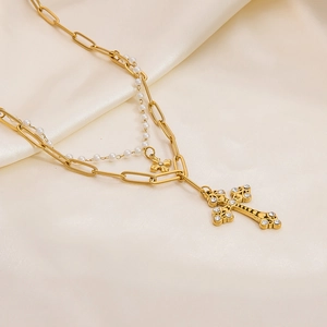 Close-up of double layer gold paperclip chain and pearl necklace with cross pendants
