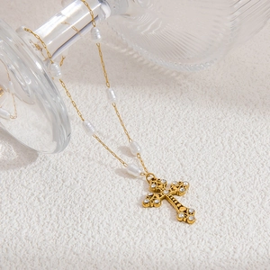 Detail of a vintage cross pendant necklace with pearls and gold paperclip chain