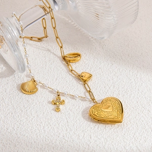 Detail of gold heart locket and cross pendants on a pearl paperclip chain necklace