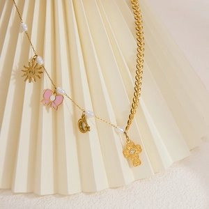 Detail of gold asymmetric necklace featuring pearl beads and multiple symbolic charms