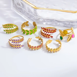 Detail of seven gold enamel leaf rings set on a textured glass tray with nature motifs