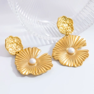 Detalle de pendientes grandes dorados con textura de abanico y perla blanca central