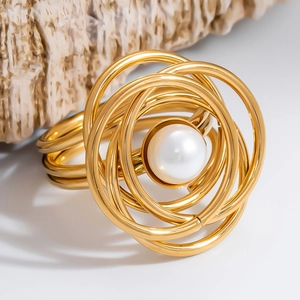 Detailed macro of gold napkin ring featuring multi-layer spiral rings and a large pearl center