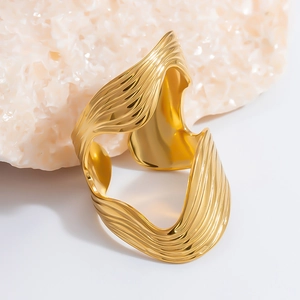 Detailed view of wide gold wave pattern cuff bracelet with vertical texture and polish