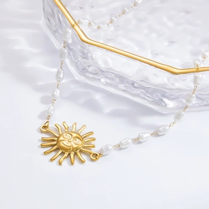 Macro detail of sun pendant pearl necklace with gold facial features and rustic chain
