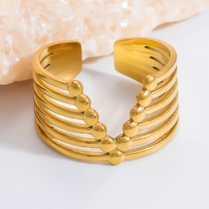 Detail of a wide gold-plated multi-layer V-shape open cuff bracelet on a marble stand