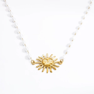 Close-up of pearl necklace featuring a golden sun face pendant with radial rays detail