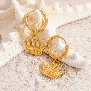 Dettaglio di orecchini con pendente a corona placcati oro 18k su sfondo di stelle marine