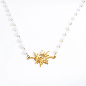 Macro shot of sunburst pendant with spiral center on baroque pearl beaded necklace