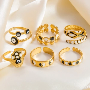 Détail d'un lot de 6 bagues dorées avec motifs émaillés œil protecteur et yin yang rétro
