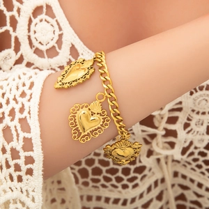 Golden Cuban chain bracelet with three ornate Sacred Heart pendants on a female wrist