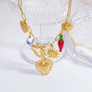 Detail of gold chain necklace with heart, sun mask, red chili, and blue ceramic pendants