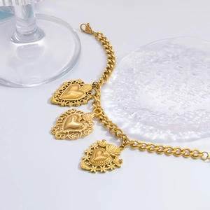 Detail of a gold stainless steel thick chain bracelet with vintage heart charms