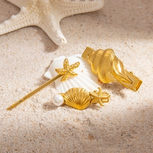 Détail des barrettes marines en or 18k avec perles et étoiles de mer sur sable