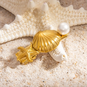 Barrette en or 18 carats avec coquillage et perle sur sable blanc au style marin