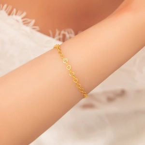 Detailed close-up of 18k gold heart-shaped hollow Cuban chain bracelet on model wrist