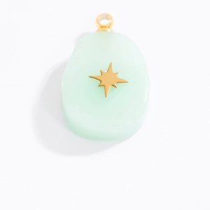 Detail view of light green oval pendant with gold star inlay and stainless steel ring