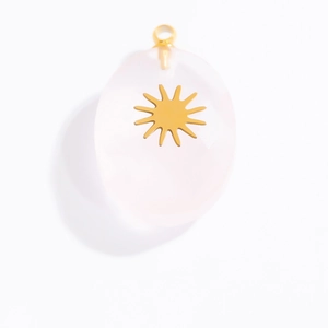 Macro detail of oval rose quartz pendant with gold sunburst inlay and top loop