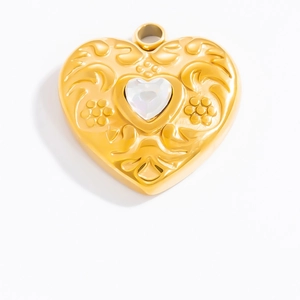 Detail of a golden heart pendant with floral embossed texture and a sparkling zircon stone