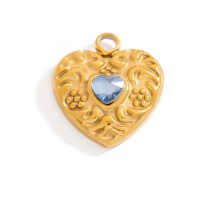 Macro shot of gold heart pendant featuring baroque floral relief and blue heart gemstone