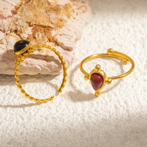 Close-up of golden adjustable rings with round black obsidian and teardrop brown stone