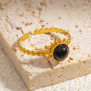 Detail of adjustable gold ring with black obsidian stone on travertine stone base