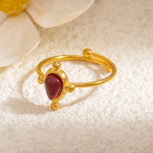 Macro detail of adjustable gold ring with red teardrop stone and retro beaded texture