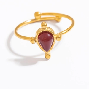 Close-up of golden adjustable ring with teardrop red gemstone and polished metallic finish