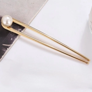 Minimalist U-shaped gold metal hair pin with large white pearl on a clean background