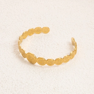 Detail of 18K gold plated stainless steel cuff bracelet with embossed radial sunburst pattern