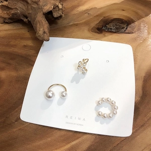 Lot de trois boucles d'oreilles ear cuffs dorées avec perles sur fond de bois