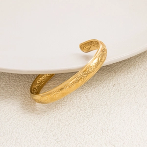 Detailed macro shot of vintage 18K gold plated C-shaped open cuff with evil eye patterns