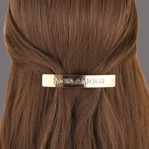 Barrette dorée avec gravure MON AMOUR présentée sur cheveux bruns pour femmes