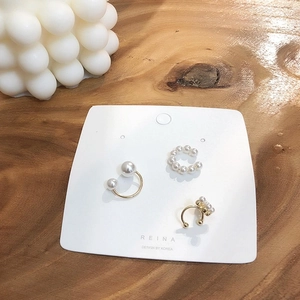 Ensemble de trois boucles d'oreilles ear cuff en perles dorées sur carte et bois