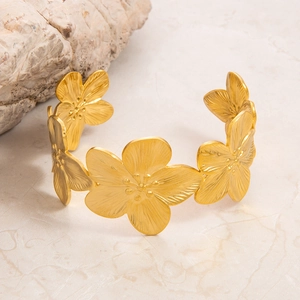Macro detail of vintage 18K gold plated bangle featuring textured five-petal floral patterns