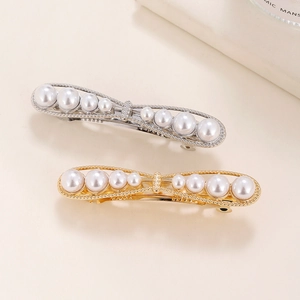 Elegant white pearl hair clips in gold and silver finishes on a neutral background