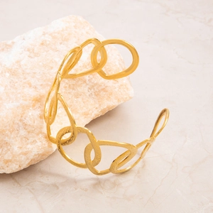Close-up of gold-plated cuff bracelet featuring organic hollow links and hammered texture