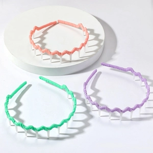 Three colorful non-slip wavy headbands with teeth on white display stands