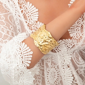Close-up of a wide 18K gold-plated cuff bracelet with a unique molten lava texture on a wrist