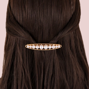 Detailed view of the gold French hair clip with white pearls on brown hair