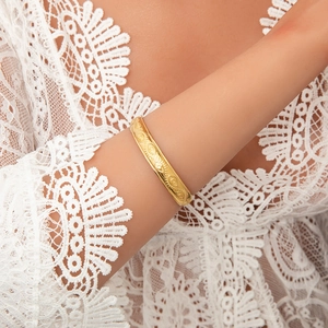 Detailed macro view of 18K gold plated bangle featuring embossed evil eye patterns