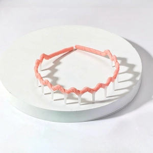 Pink wave-shaped fabric headband with white anti-slip comb teeth on a display stand