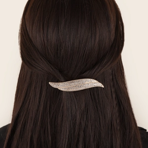 Elegant gold leaf spring hair clip with sparkling rhinestones worn on brunette hair
