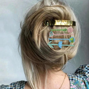 Dettaglio di un fermaglio per capelli in metallo dorato con spille a fiori colorati su modella