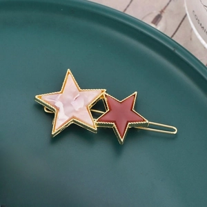 Gros plan d'une barrette étoile dorée avec marbre rose et étoiles rouge foncé