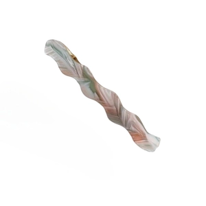 Détail de la pince à cheveux ondulée en acétate avec marbrure rose vert et clip doré