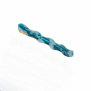 Gros plan sur la barrette ondulée en acétate vert avec motif marbré et base dorée